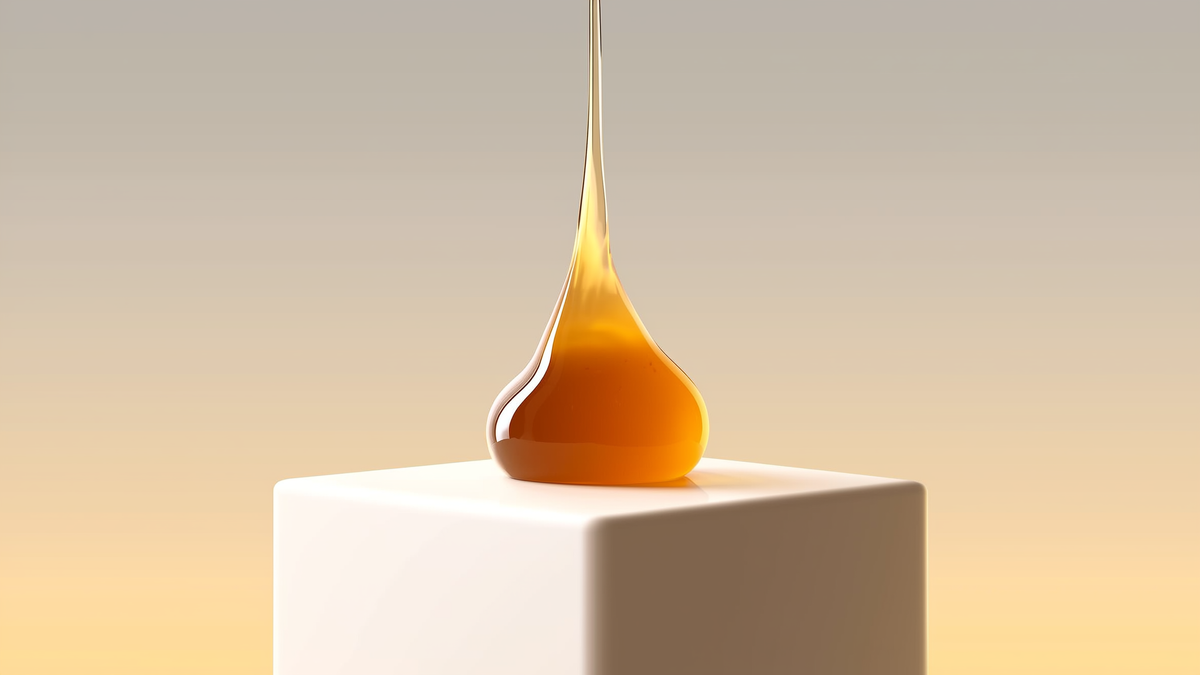 A thick amber resin drop forming a teardrop shape on a white pedestal with pastel background.
